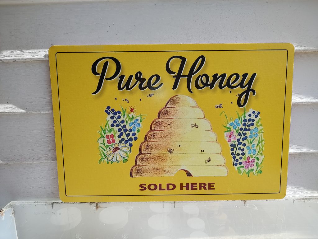 Yellow sign that reads Pure Honey sold here