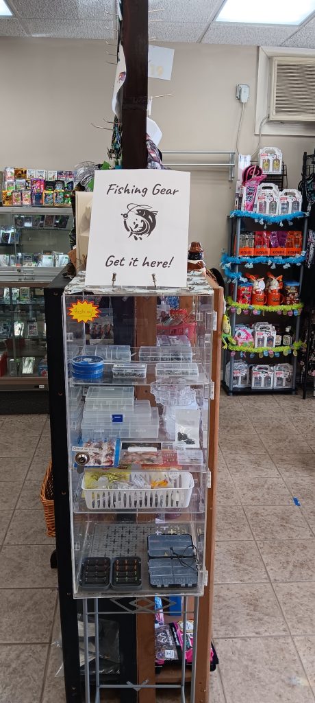 Display with sign that reads Fishing Gear get it here! Display holds various tackle and fishing gear